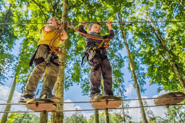 Dois rapazinhos num parque de cordas. Recreação física ativa da criança ao ar livre no parque. Treinamento para crianças — Fotografia de Stock