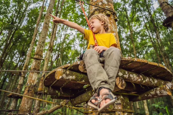 Un niño en un parque de cuerdas. Recreación física activa del niño al aire libre en el parque. Formación para niños — Foto de Stock