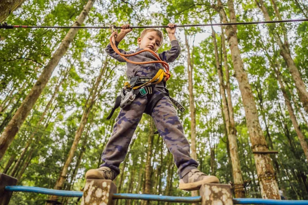 Um rapazinho num parque de cordas. Recreação física ativa da criança ao ar livre no parque. Treinamento para crianças — Fotografia de Stock