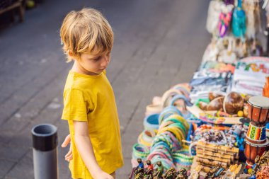 Ubud, Bali'de bir markette çocuk. Ünlü Ubud Market, Endonezya'da Hediyelik eşya ve Bali el sanatları satan tipik hediyelik eşya dükkanı. Bali pazarı. Yerel sakinlerinin ahşap ve el sanatları Hediyelik eşya
