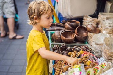 Ubud, Bali'de bir markette çocuk. Ünlü Ubud Market, Endonezya'da Hediyelik eşya ve Bali el sanatları satan tipik hediyelik eşya dükkanı. Bali pazarı. Yerel sakinlerinin ahşap ve el sanatları Hediyelik eşya