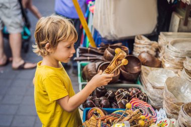 Ubud, Bali'de bir markette çocuk. Ünlü Ubud Market, Endonezya'da Hediyelik eşya ve Bali el sanatları satan tipik hediyelik eşya dükkanı. Bali pazarı. Yerel sakinlerinin ahşap ve el sanatları Hediyelik eşya