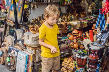 Ubud, Bali'de bir markette çocuk. Ünlü Ubud Market, Endonezya'da Hediyelik eşya ve Bali el sanatları satan tipik hediyelik eşya dükkanı. Bali pazarı. Yerel sakinlerinin ahşap ve el sanatları Hediyelik eşya