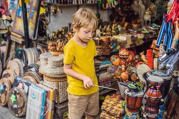 Boy at a market in Ubud, Bali. Typical souvenir shop selling souvenirs and handicrafts of Bali at the famous Ubud Market, Indonesia. Balinese market. Souvenirs of wood and crafts of local residents — Stock Photo, Image