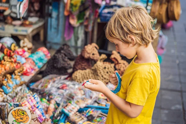 Chlapec na trhu v Ubud, Bali. Typický obchod se suvenýry prodává suvenýry a řemeslné výrobky z Bali na slavném Ubuda Market, Indonésie. Balijské tržiště. Suvenýry ze dřeva a řemesel místních obyvatel — Stock fotografie