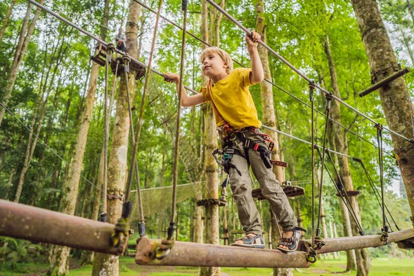 Chlapeček v lanové parku. Aktivní fyzické rekreace dítěte v čerstvém vzduchu v parku. Školení pro děti — Stock fotografie