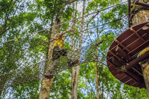 Um rapazinho num parque de cordas. Recreação física ativa da criança ao ar livre no parque. Treinamento para crianças — Fotografia de Stock