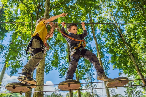 Dva malí hoši v lanové parku. Aktivní fyzické rekreace dítěte v čerstvém vzduchu v parku. Školení pro děti — Stock fotografie