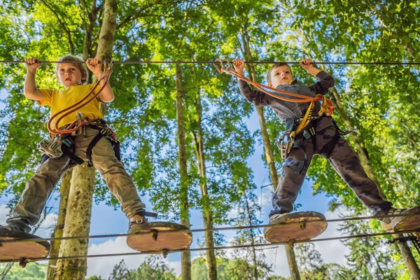 Due ragazzini in un parco di corde. Ricreazione fisica attiva del bambino all'aria aperta nel parco. Formazione per bambini — Foto Stock