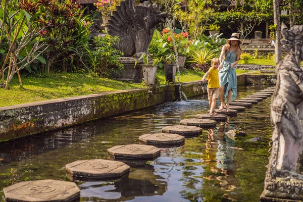 Anya és fia turisták Taman Tirtagangga, víz palota, vízi park, Bali Indonézia. Utazótáska-val gyerekek fogalom. Gyerekbarát hely — Stock Fotó