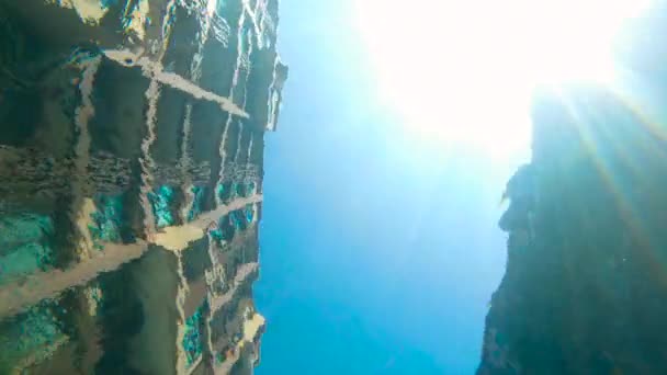 Slomotion shot. Vista desde el fondo de una piscina sobre los edificios que la rodean y el sol brillando a través del agua — Vídeo de stock