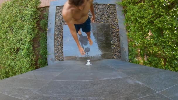 Slowmotion strzał młodego mężczyzny, który bierze prysznic w tropikalnym ogrodzie. Wakacje w tropikalnym ośrodku koncepcji. Młody człowiek Vlogger robi a wideo z sam biorąc a prysznic w a tropikalny hotel — Wideo stockowe