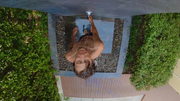 열대 정원에서 샤워를하는 젊은 남자의 슬로우 모션 샷. 열대 리조트 개념의 휴일. 젊은 남자 동영상 블로거 는 열대 호텔에서 샤워를 복용 자신의 비디오를 만든다 — 비디오
