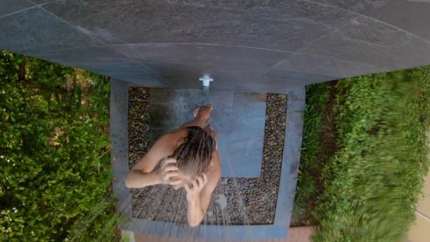 La toma en cámara lenta de una joven toma una ducha en un jardín tropical. Vacaciones en un concepto de resort tropical. Joven vlogger hace un video de sí misma tomando una ducha en un hotel tropical — Vídeo de stock