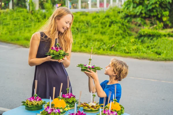 ママと息子の観光客は、彼女の手にロイクラトンを保持し、水にそれを起動しようとしている。ロイ・クラトン・フェスティバル、人々はロイを祝うために光と水に浮かぶために花とろうそくを買います — ストック写真