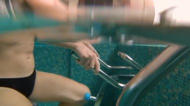 Bir sualtı su su egzersiz bisiklet ve su koşu bandı üzerinde egzersizleri yapan genç bir kadının slowmotion çekim. Aqua spor egzersizleri kavramı