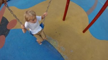 Oğlunu salıncakta sallayan bir babanın yavaş çekim vuruşu. Çocukluk kavramı