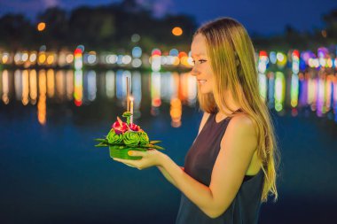 A female tourist holds the Loy Krathong in her hands and is about to launch it into the water. Loy Krathong festival, People buy flowers and candle to light and float on water to celebrate the Loy clipart