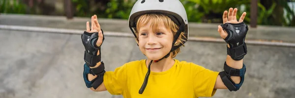 Atletico ragazzo in casco e ginocchiere impara a skateboard con in uno skate park. Educazione dei bambini, sport BANNER, FORMATO LUNGO — Foto Stock