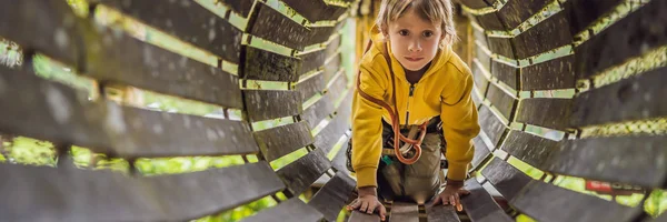 Little boy in a rope park. Active physical recreation of the child in the fresh air in the park. Training for children BANNER, LONG FORMAT — Stock Photo, Image
