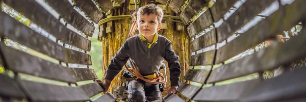 Kleiner Junge in einem Seilpark. Aktive körperliche Erholung des Kindes an der frischen Luft im Park. Schulung für Kinder Banner, Langformat — Stockfoto