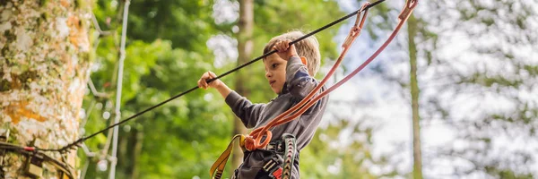 Un ragazzino in un parco di corde. Ricreazione fisica attiva del bambino all'aria aperta nel parco. Formazione per bambini BANNER, FORMATO LUNGO — Foto Stock