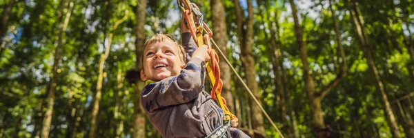 Um rapazinho num parque de cordas. Recreação física ativa da criança ao ar livre no parque. Treinamento para crianças BANNER, LONG FORMAT — Fotografia de Stock