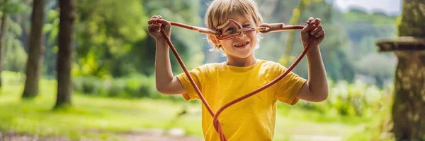 Un niño en un parque de cuerdas. Recreación física activa del niño al aire libre en el parque. Formación para niños BANNER, FORMATO LARGO — Foto de Stock