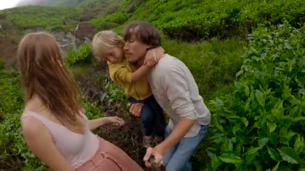 スローモーションショット。若いカップルとその息子は山の大きな茶畑に立って自分撮りを作ります — ストック動画