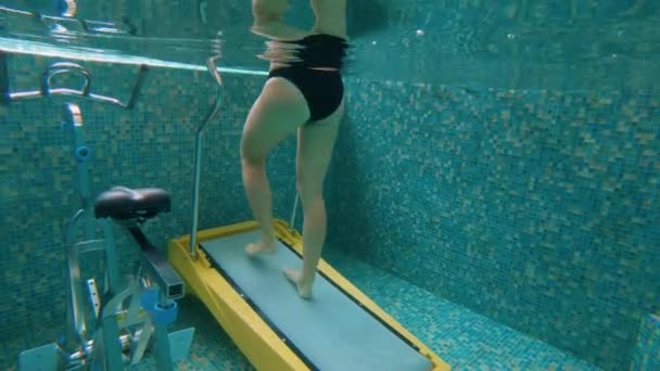 KUALA LUMPUR, MALAYSIA - 25 апреля 2018 года. Медленный снимок молодой женщины, делающей упражнения на подводной водной беговой дорожке. Концепция водных видов спорта — стоковое видео