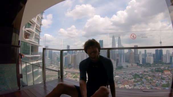 Slowmotion Shot. Молодий чоловік робить селфі сидить на точку зору з видом на центр Куала-Лумпура. Подорож до Малайзії концепція — стокове відео