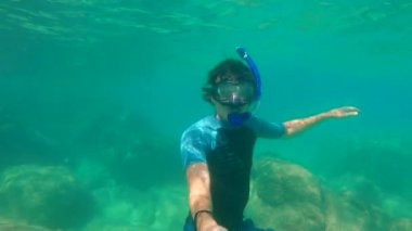 Genç adam güzel bir mavi denizde homurdanıyor ve bir selfie video yapar