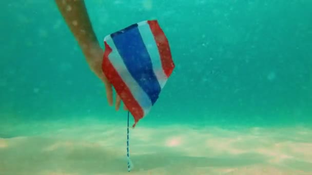 Slowmotion tiro de um homem mergulho snorkeler e colocando a bandeira da Tailândia no fundo do mar. Bandeira cercada por peixes tropicais. Viaje para o conceito Tailândia. Mergulho e snorkeling em Tailândia — Vídeo de Stock