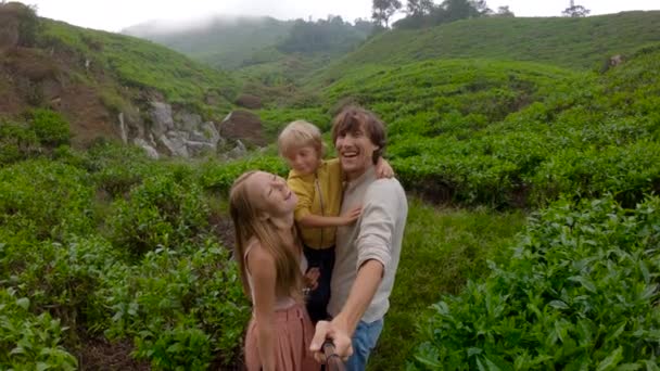 Perlahan-lahan. Pasangan muda dan anaknya berfoto selfie berdiri di perkebunan teh besar di pegunungan — Stok Video