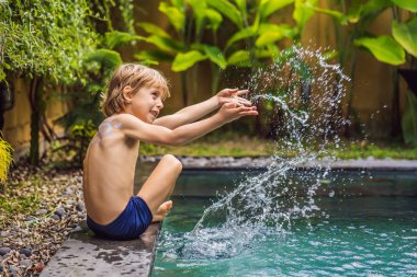Havuz başında oynarken omzunda güneş kremi ile boyanmış güneş ile mutlu çocuk. Yaz tatili konsepti. Metin için alan