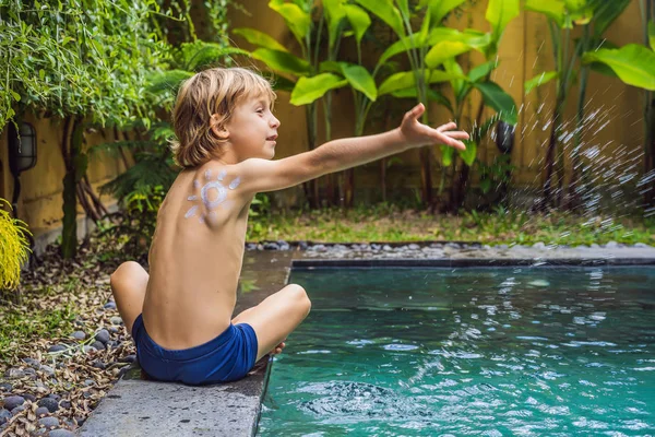 Szczęśliwy chłopiec z słońcem malowane przez krem do opalania na ramię grając przy basenie. Koncepcja wakacji letnich. Miejsce na tekst — Zdjęcie stockowe
