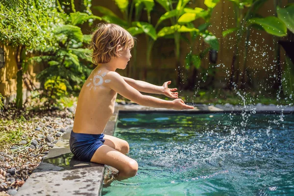Havuz başında oynarken omzunda güneş kremi ile boyanmış güneş ile mutlu çocuk. Yaz tatili konsepti. Metin için alan