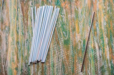 Steel drinking vs disposable straws on painted wooden background. Zero waste concept