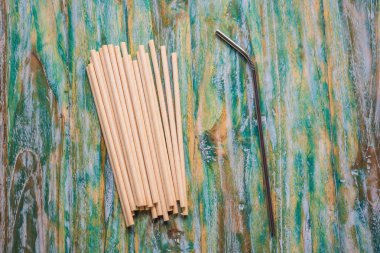Steel drinking vs disposable straws on painted wooden background. Zero waste concept
