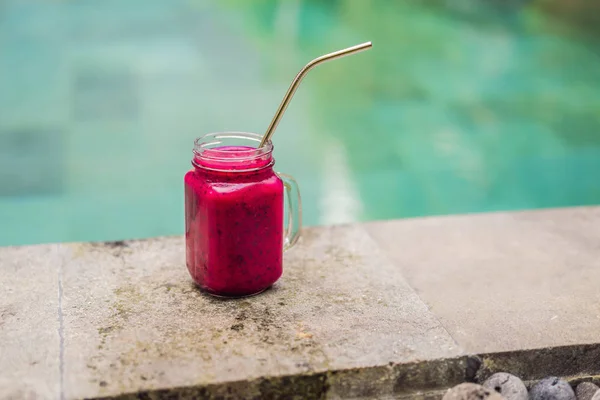 Frullato di frutta drago con paglia da bere in acciaio sullo sfondo della piscina — Foto Stock