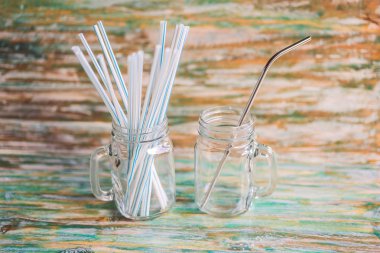 Steel drinking vs disposable straws on painted wooden background. Zero waste concept