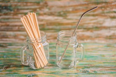Steel drinking vs disposable straws on painted wooden background. Zero waste concept