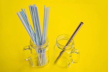 Sarı arka planda çelik içki ve tek kullanımlık pipetler. Sıfır atık