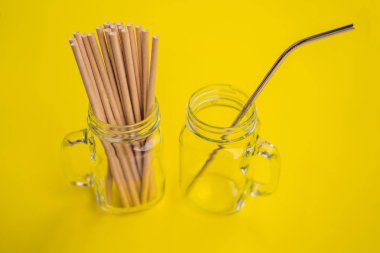 Sarı arka planda çelik içki ve tek kullanımlık pipetler. Sıfır atık