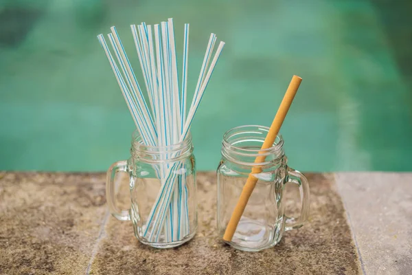 Bamboo drinking straw vs disposable straws on the background of the pool. Zero waste concept