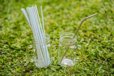 Çelik içme vs çim arka plan üzerinde tek kullanımlık pipetler. Sıfır atık kavramı