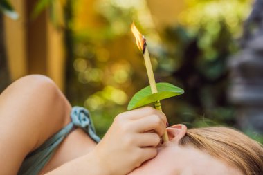Spa'da çekici beyaz bir kadına kulak asmları yapılıyor.