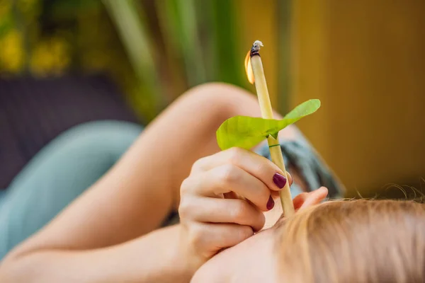 Vela de oreja que se lleva a cabo en una atractiva mujer caucásica en un spa — Foto de Stock