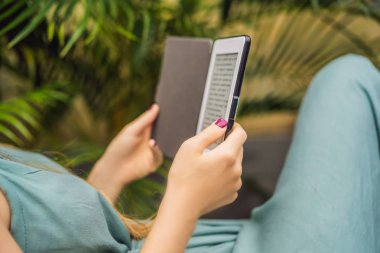 Kadın bahçede şezlong üzerinde e-kitap okur