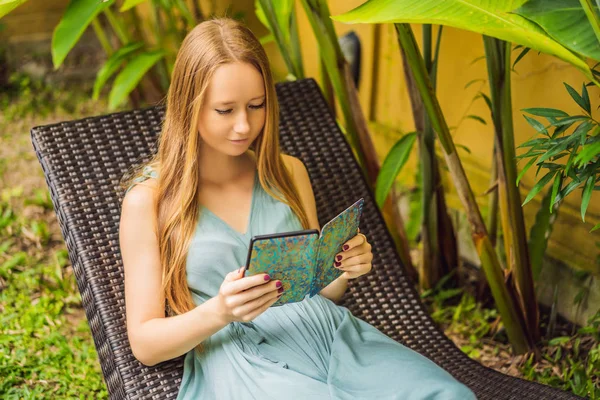 Femme lit e-book sur chaise longue dans le jardin — Photo